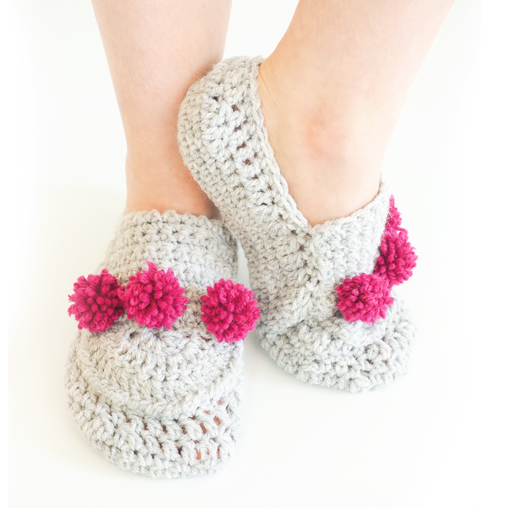 These crochet pom pom slippers are a one size fits all, and are extra comfy. This crochet pattern is easy to make and cozy to wear. #CrochetSlippers #CrochetPattern #CrochetAddict