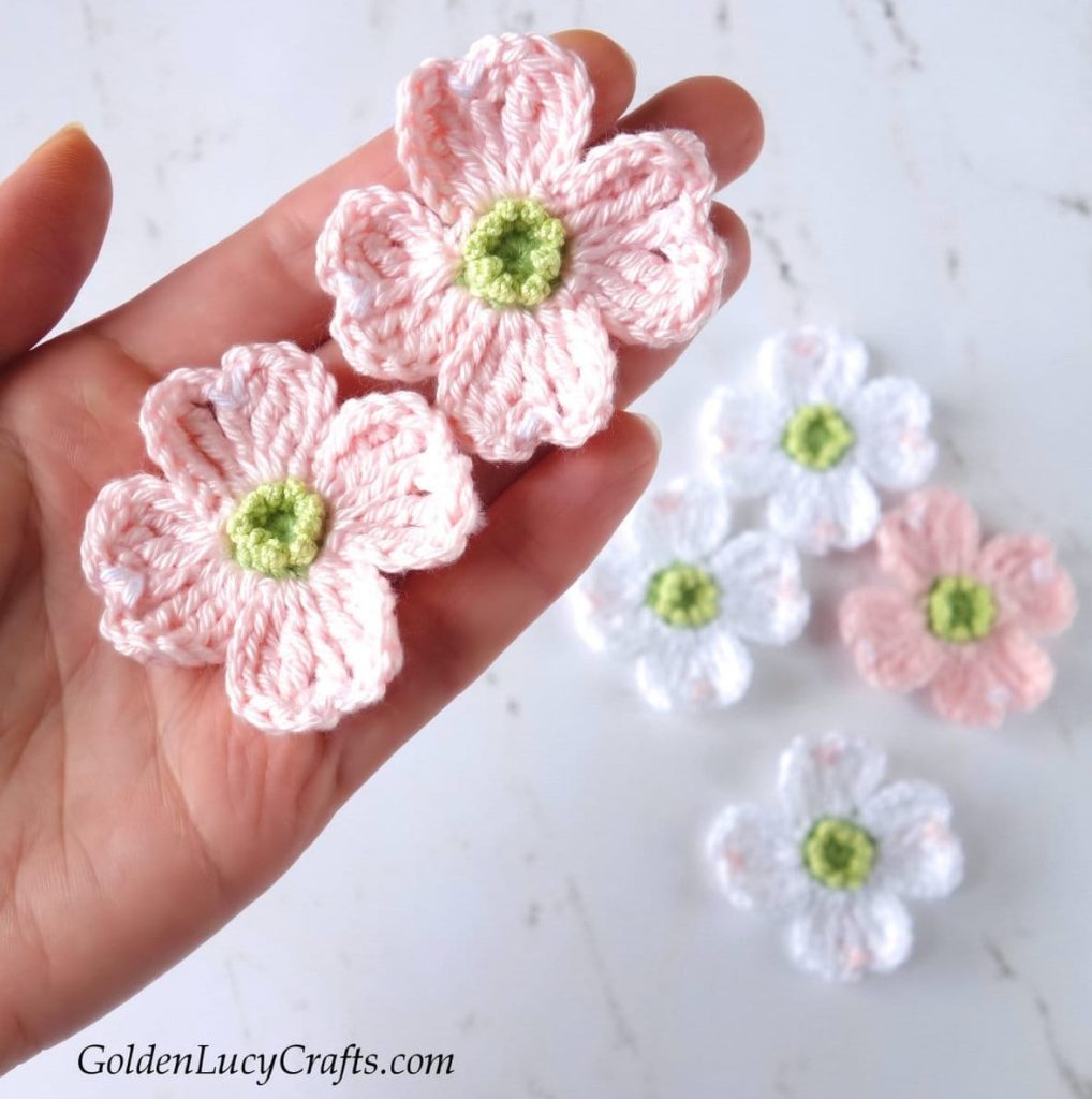 hand carrying Crochet Dogwood Flowers with more flowers in the background