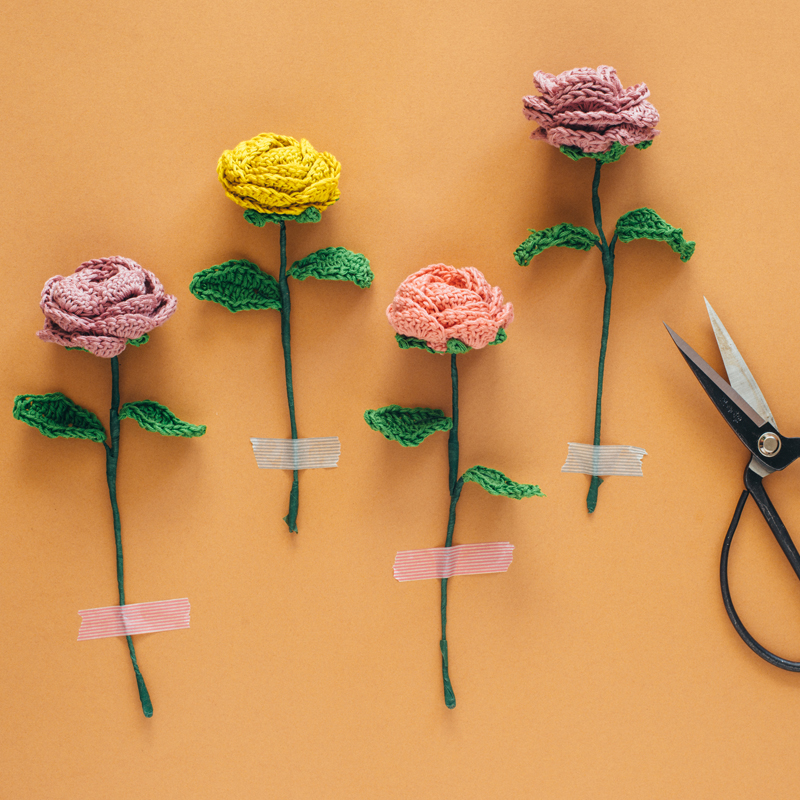 Crochet Flowers taped to an orange background next to scissors