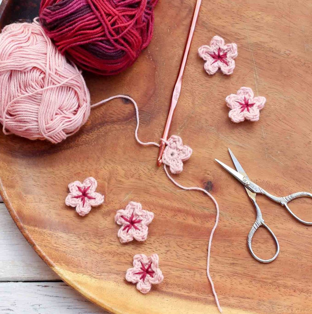 Crochet Cherry Blossoms with yarns, scissors, and crochet hook